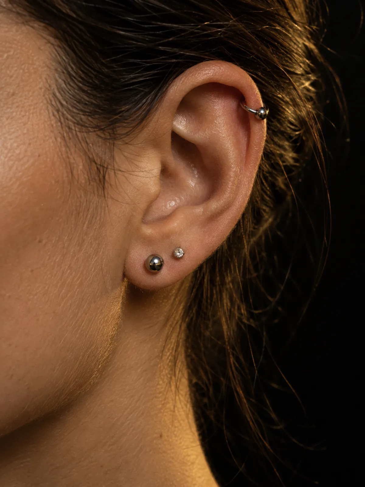 Oreille portant un piercing hélix et deux lobes en titane